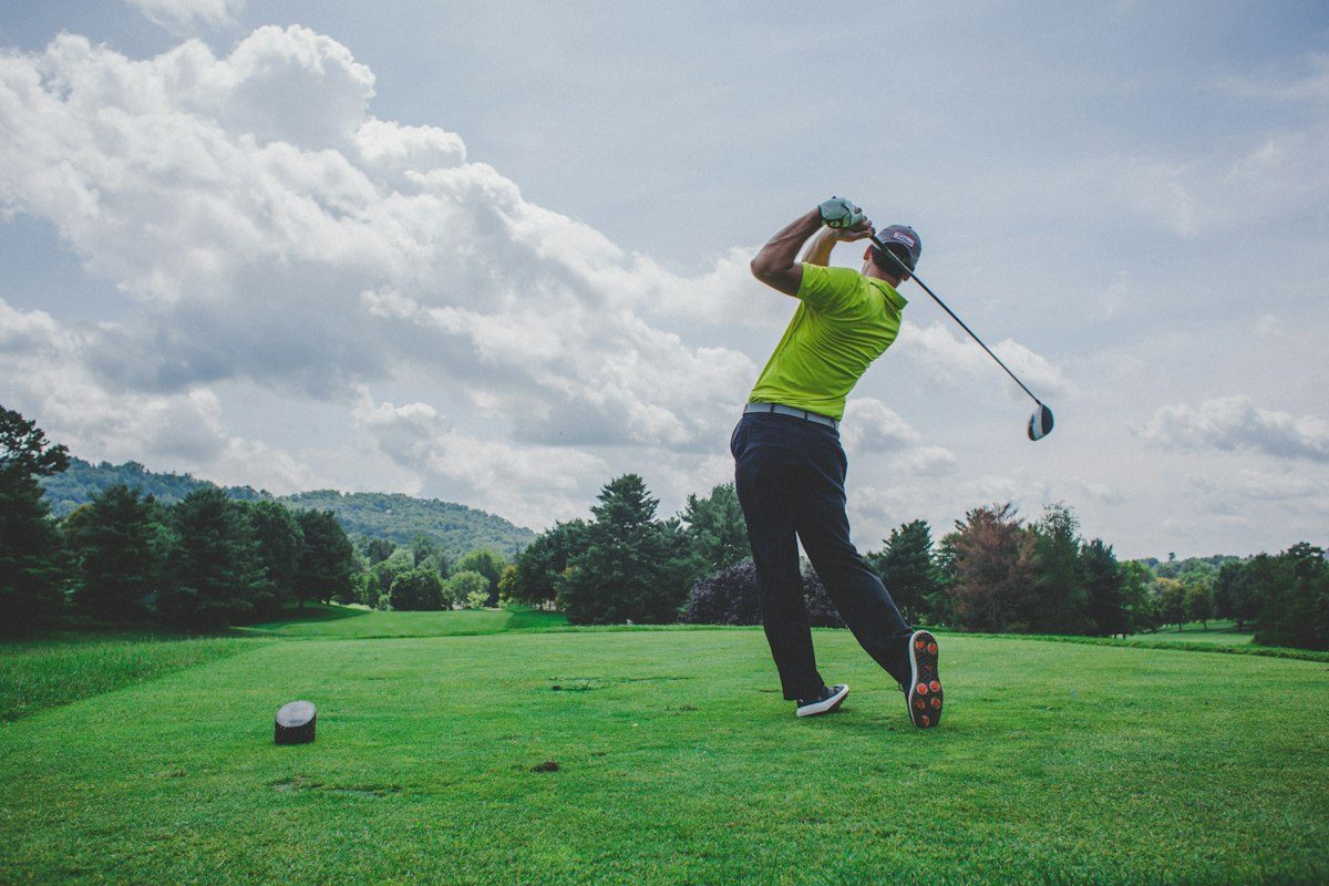 Golfer teeing off on a green fairway